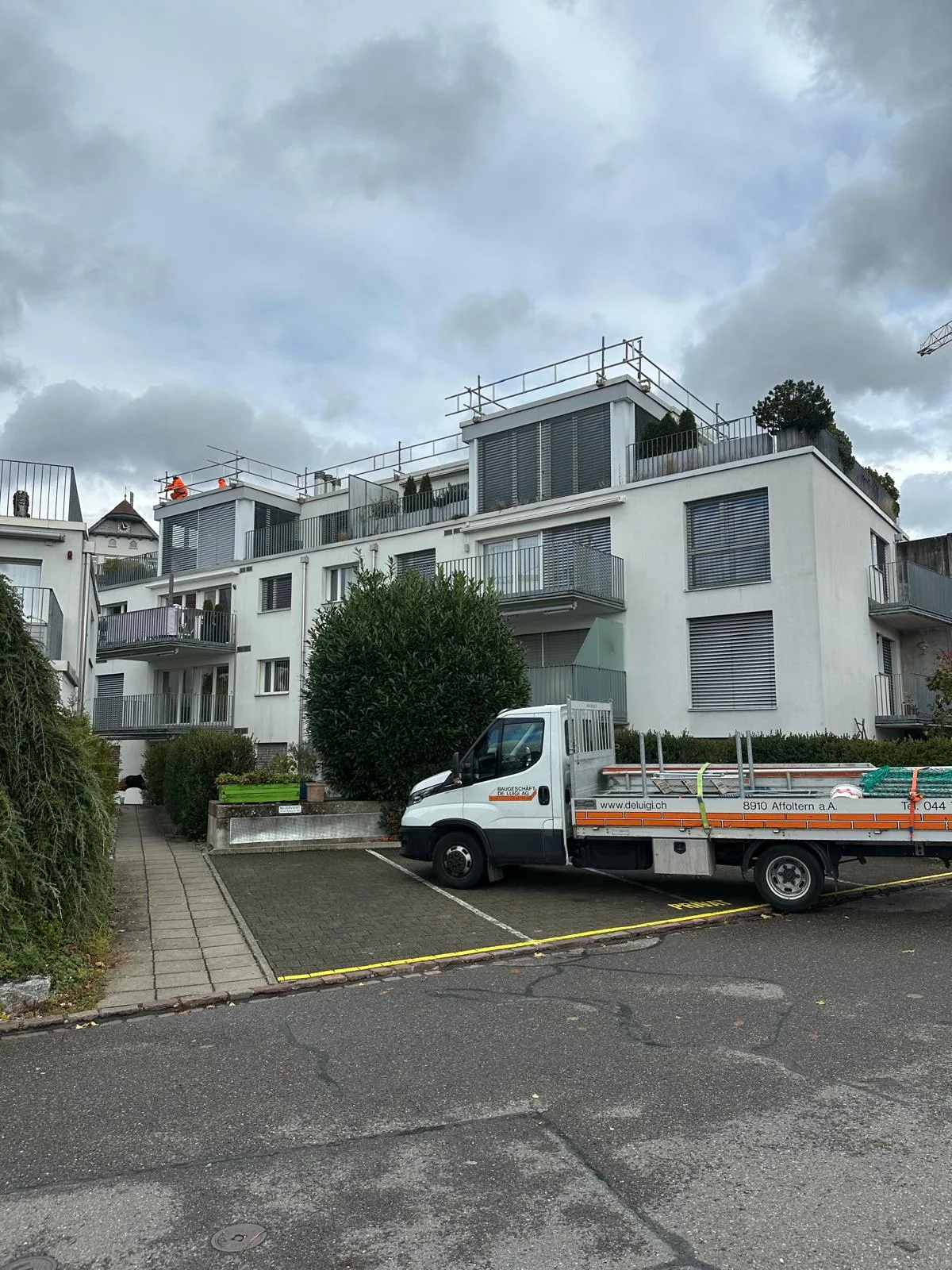 De Luigi Transportfahrzeug mit Gerüstmaterial vor MFH