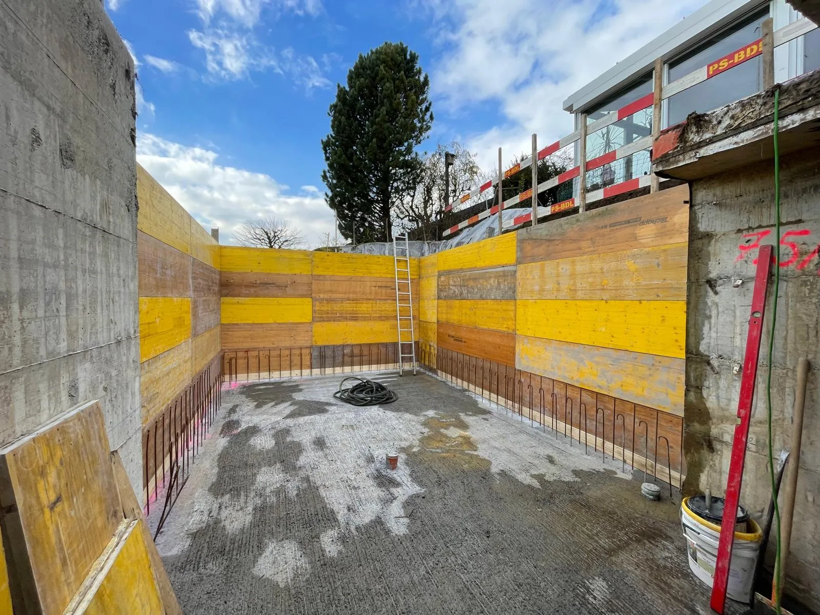 Baugrube mit Schalung und Armierungseisen für neue Betonwand